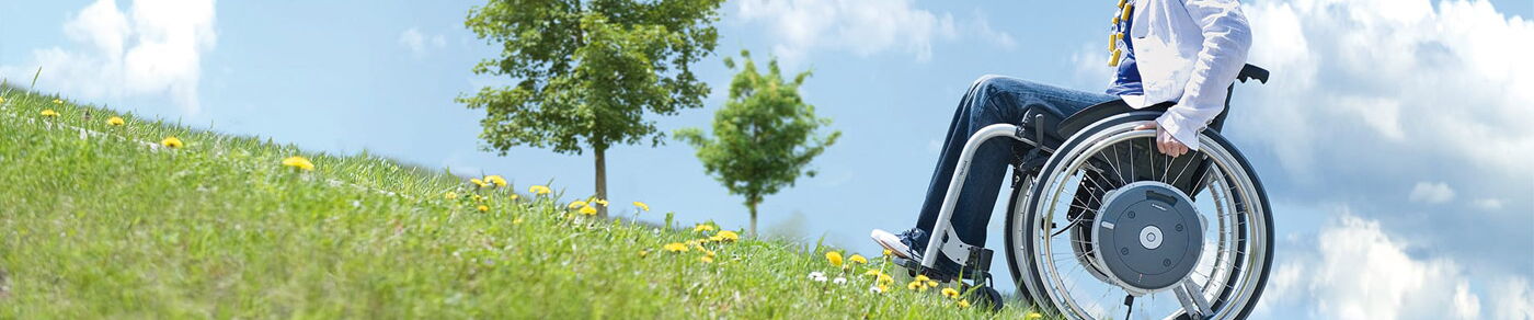 Layout Seitenkopf  E-Motion Person mit Rollstuhl fährt eine Berg h och